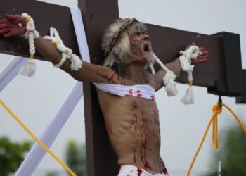 Clavado en una cruz, filipino reza para que termine la guerra en Ucrania
