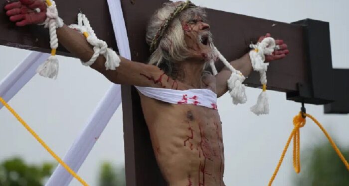 Clavado en una cruz, filipino reza para que termine la guerra en Ucrania